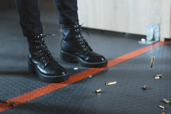 Cropped image of woman standing near red line and falling bullets in shooting range — Stock Photo