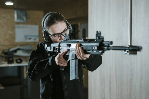 Niña apuntando rifle en el campo de tiro - foto de stock