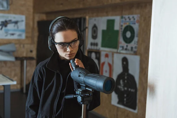 Attractive woman with binoculars in shooting range — Stock Photo