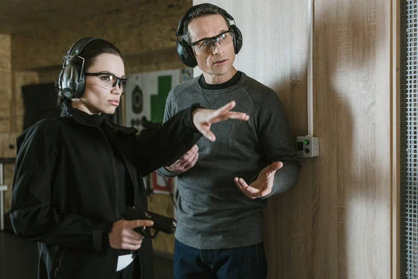 Female instructor showing where shoot to client in shooting range — Stock Photo