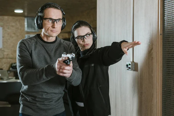 Female instructor showing where shoot to client in shooting range — Stock Photo