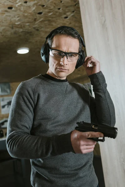 Handsome man with gun in shooting range — Stock Photo