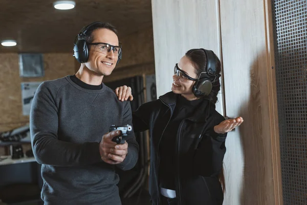 Instructeur de tir souriant soutenant le client dans la galerie de tir — Photo de stock