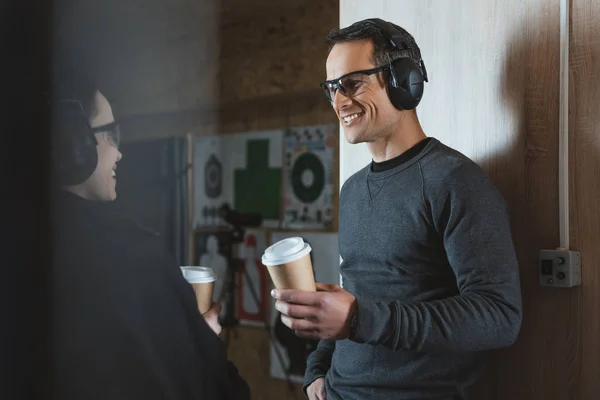 Smiling customer and shooting instructor drinking coffee in shooting range — Stock Photo