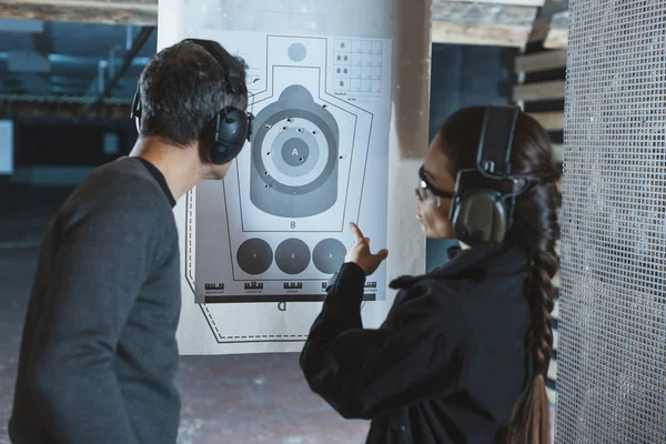 Shooting instructor pointing on used target in shooting range — Stock Photo