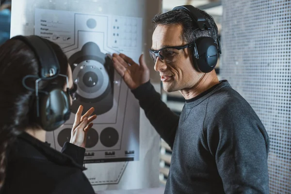 Shooting instructor showing on used target with holes — Stock Photo