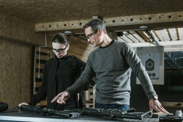 Instructor pointing on rifle on table in shooting range — Stock Photo