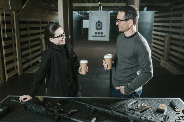 Smiling customer and shooting instructor drinking coffee in shooting range — Stock Photo