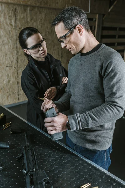 Instructor showing rifle magazine to client in shooting gallery — Stock Photo