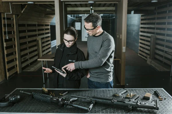 Istruttore mostrando pistola al cliente nel poligono di tiro — Foto stock