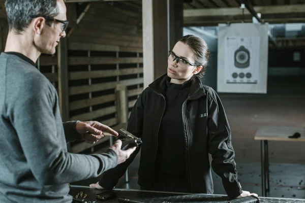 Instrutor descrevendo arma para cliente feminino no intervalo de tiro — Stock Photo