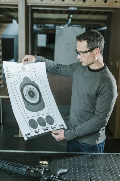 Shooter looking at used target after shooting in gallery — Stock Photo