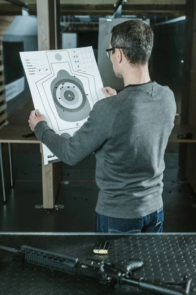 Rear view of shooter looking at used target after shooting in shooting range — Stock Photo