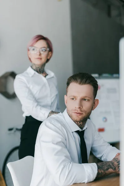 Jovem tatuado negócios pessoas em formal desgaste olhando para longe no escritório — Fotografia de Stock