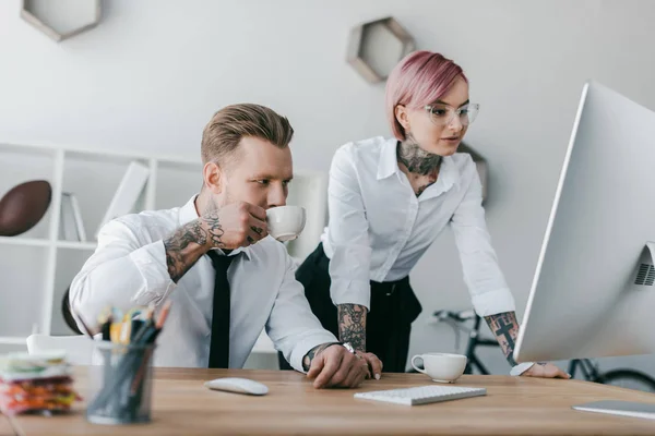 Giovani uomini d'affari tatuati utilizzando computer desktop insieme — Foto stock