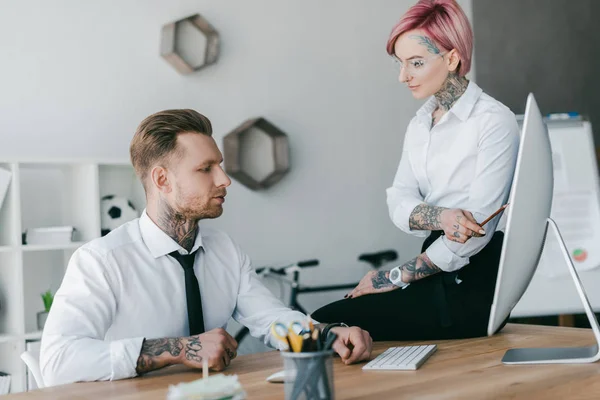 Joven hombre de negocios y mujer de negocios con tatuajes trabajando juntos en la oficina - foto de stock