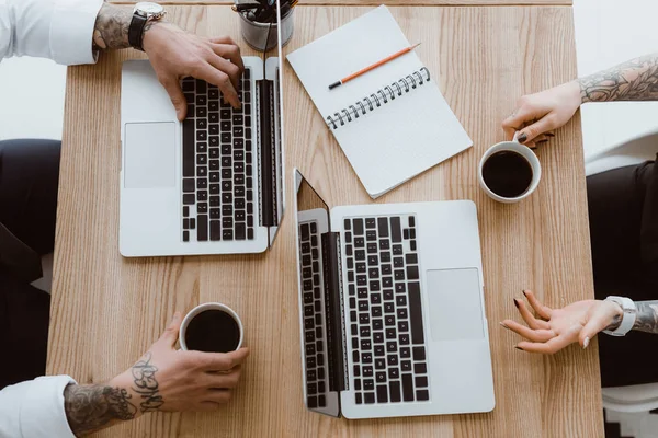 Vue de dessus des collègues utilisant des ordinateurs portables et boire du café — Photo de stock