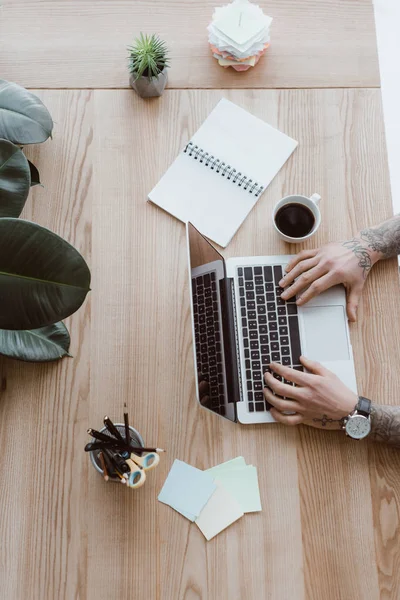 Cropped shot of tattooed man using laptop at workplace — Stock Photo