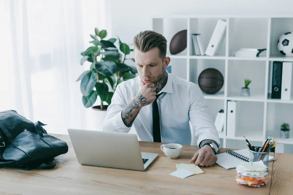 Konzentrierter Jungunternehmer mit Laptop im Büro — Stockfoto