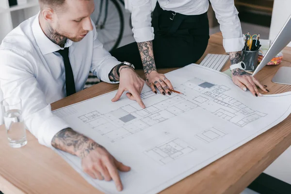 Cropped shot of young business people working with blueprint in office — Stock Photo