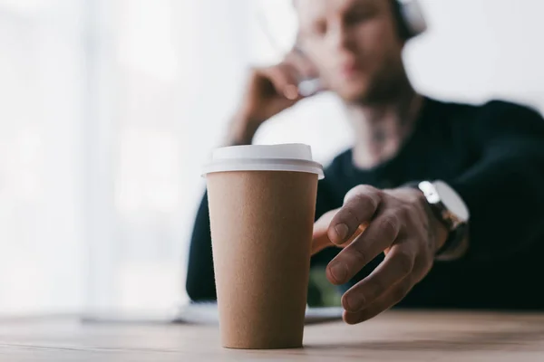 Close-up view of young businessman reaching for paper cup on table — Stock Photo