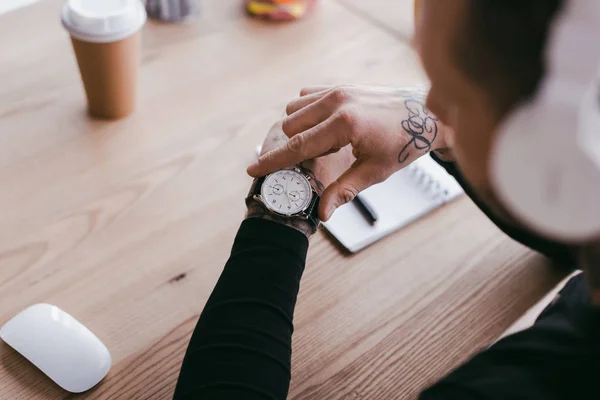 Selective focus of young businessman checking wristwatch at workplace — Stock Photo