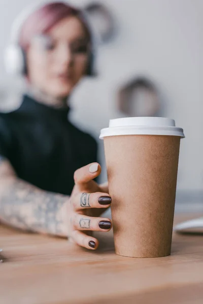 Крупним планом молода бізнес-леді з татуюваннями тримає паперовий стаканчик — стокове фото