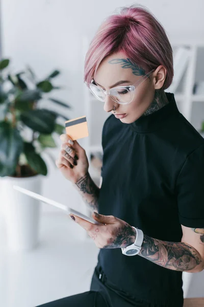 Jovem empresária tatuada segurando cartão de crédito e usando — Fotografia de Stock