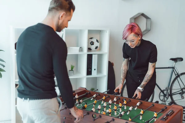 Young tattooed colleagues playing foosball in office — Stock Photo