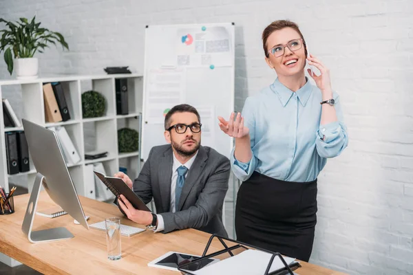 Hombre de negocios tratando de trabajar mientras su colega habla por teléfono y lo molesta - foto de stock