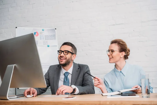 Rire entreprise heureuse de travailler avec l'ordinateur ensemble au bureau moderne — Photo de stock