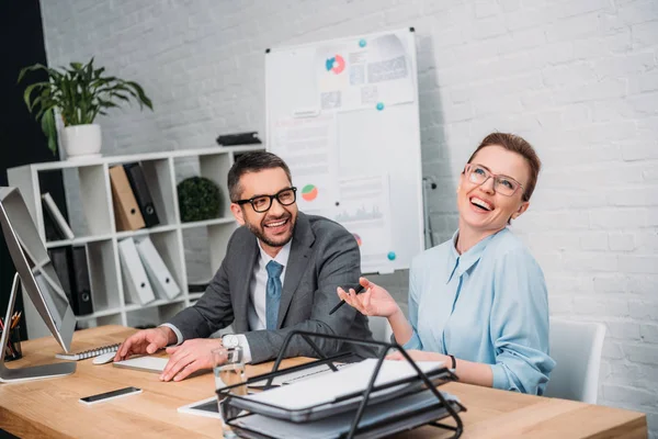 Riendo felices socios de negocios en la oficina moderna - foto de stock