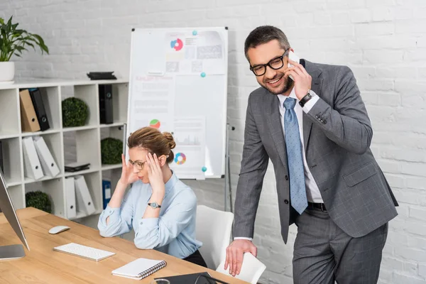 Businessman talking by phone while his annoyed colleague trying to work — Stock Photo