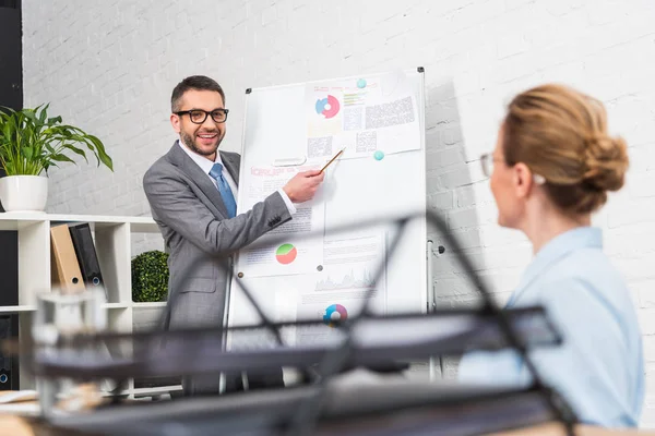 Smiling handsome businessman making presentation with whiteboard for colleague at office — Stock Photo