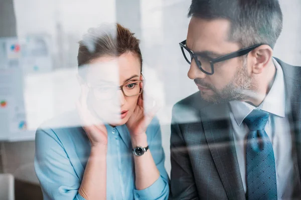 Young business partners talking behind glass — Stock Photo