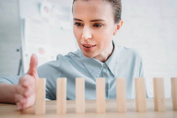 Nahaufnahme einer Geschäftsfrau, die Holzklötze hintereinander auf einem Arbeitstisch montiert, Konzept mit Dominoeffekt — Stockfoto