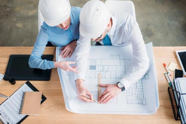 Vista de ángulo alto de los arquitectos que trabajan con el plan de construcción juntos en la oficina - foto de stock