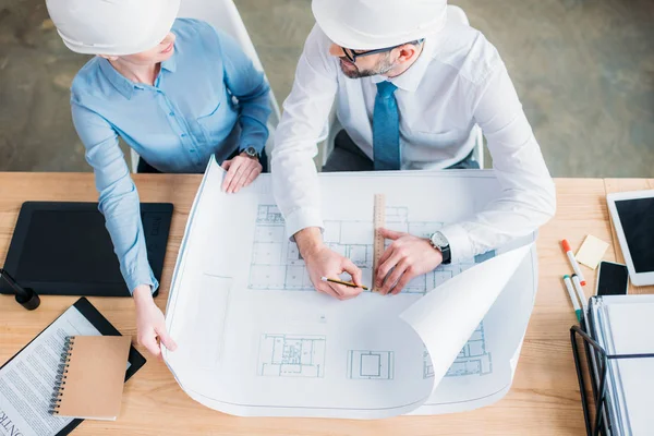 Vista de ángulo alto de arquitectos experimentados que trabajan con el plan de construcción en la oficina - foto de stock