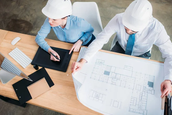 Hochwinkelaufnahme von Architekten, die mit Bauplan und Zeichnungstablette im Büro arbeiten — Stockfoto