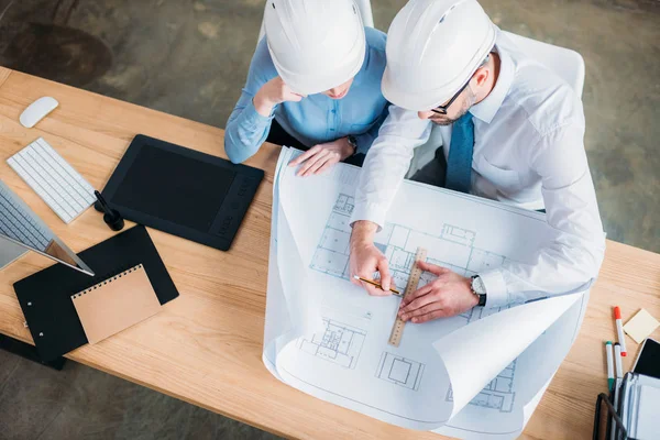 High angle view of architects in hard hats working with building plan at office — Stock Photo