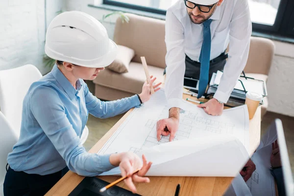 Vista de ángulo alto de los arquitectos que trabajan con el plan de construcción en la oficina - foto de stock