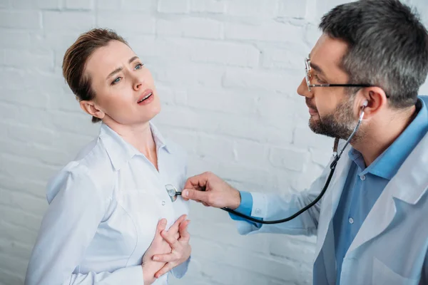 Doctor escuchando latidos del corazón de patente con estetoscopio - foto de stock