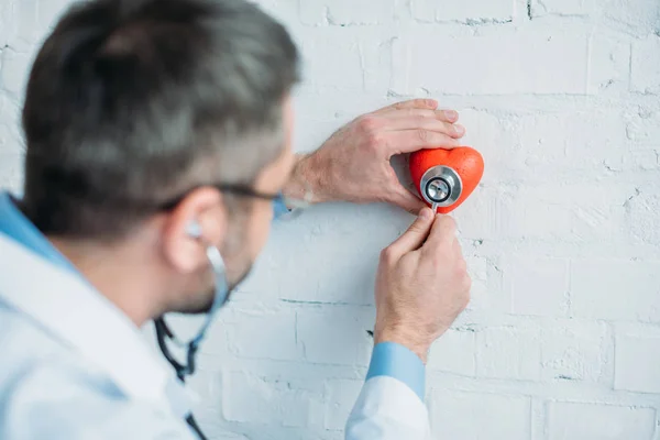 Doctor listening heartbeat of toy heart with stethoscopes — Stock Photo