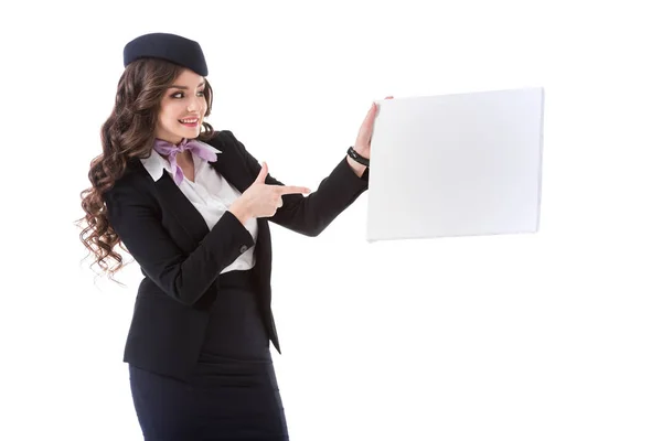 Beautiful stewardess pointing on empty board isolated on white — Stock Photo