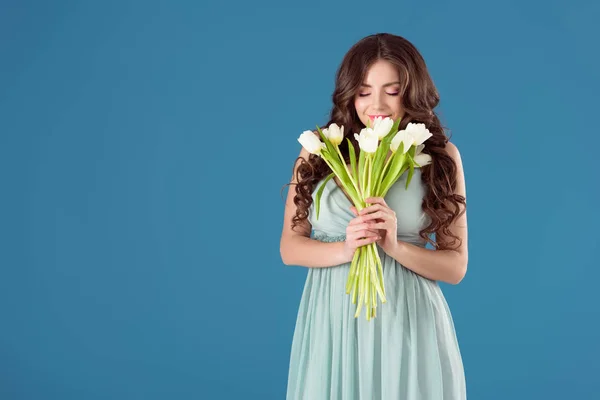 Menina bonita farejando tulipas isoladas em azul — Fotografia de Stock