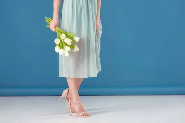 Cropped image of girl holding bouquet of tulips on blue — Stock Photo