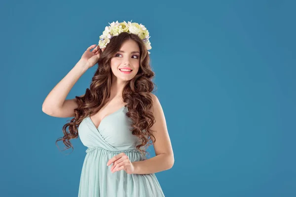 Усміхнена красива дівчина з квітковим вінком на голові ізольована на синьому — стокове фото