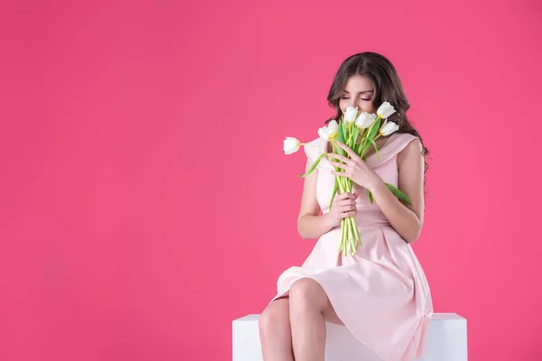Chica atractiva olfateando ramo de tulipanes aislados en rosa - foto de stock