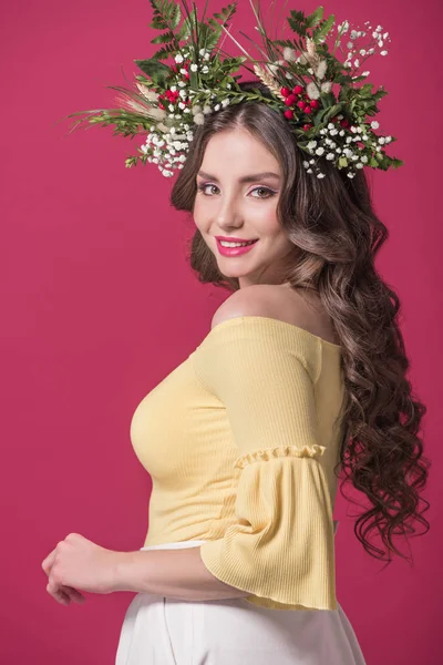 Schöne Mädchen mit Blumenkranz auf dem Kopf schaut in die Kamera isoliert auf Burgund — Stockfoto