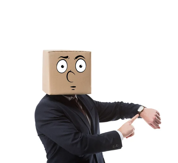 Hombre de negocios con caja de cartón en la cabeza apuntando en reloj de pulsera aislado en blanco - foto de stock